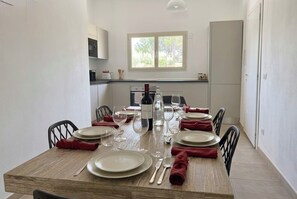 Een eetgedeelte met een houten tafel voor vier personen, compleet met borden, bestek en wijnglazen.