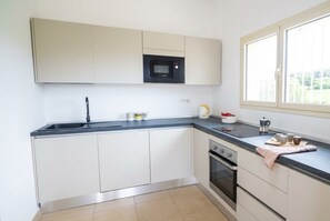 Een keuken met een inbouwmagnetron, een spoelbak en een kookplaat.