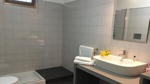 Une salle de bain moderne avec un lavabo blanc, une douche en verre et des toilettes blanches.