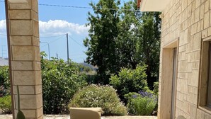 Un espace extérieur aménagé en terrasse, avec un sol carrelé de couleur beige, des meubles blancs et une plante en pot.