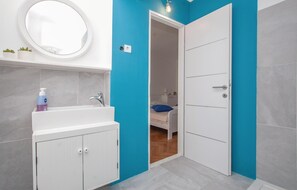 Ein Badezimmer mit einem weißen Waschbecken, einem Spiegel und einer blauen Wand.
