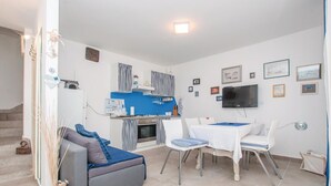 Un espai habitable compacte amb una cuineta, zona de dinar i sofà.