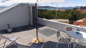 Terrassa al terrat amb un para-sol blanc, una taula petita i dues cadires còmodes.