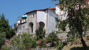 Ein mehrstöckiges Gebäude mit einer Stein-Fassade, Bogenfenstern und Balkonen mit grünen Fensterläden.