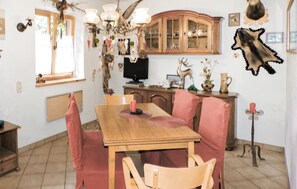 Enjoy meals in this traditional dining area with a wooden table and matching chairs, a mounted animal head, and a TV on the cabinet.