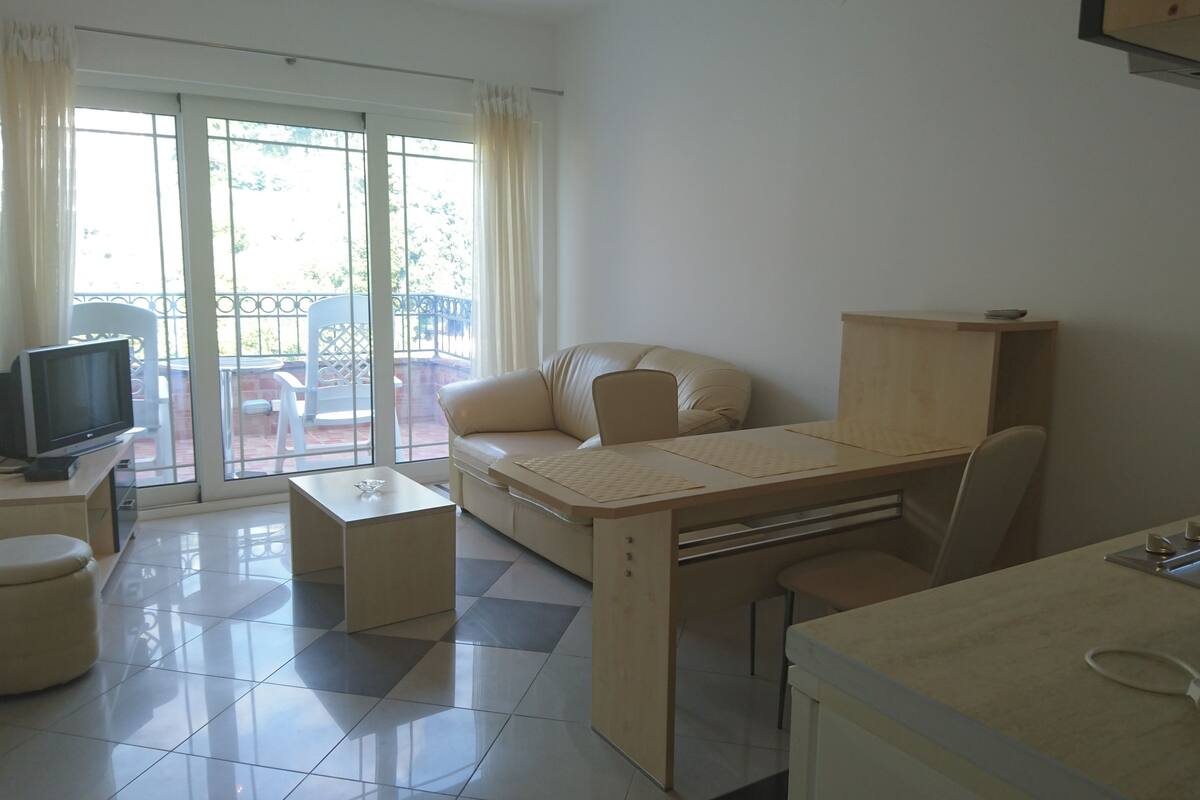 A compact living space with a sofa, a small TV, a desk with a keyboard, and a chair.