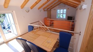 A compact room with a wooden ceiling, a small table with chairs, a window, and a TV. - Springs apartments (Pržno)