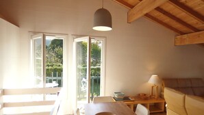 A bright kitchen with wooden beams, a dining table, chairs, and a sofa. - Sunny garden apartment in a breathtaking location (Saint-Pée-sur-Nivelle)