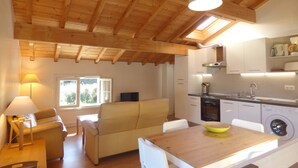A modern kitchen with wooden beams, a dining area with a table and chairs, and a sofa. - Sunny garden apartment in a breathtaking location (Saint-Pée-sur-Nivelle)