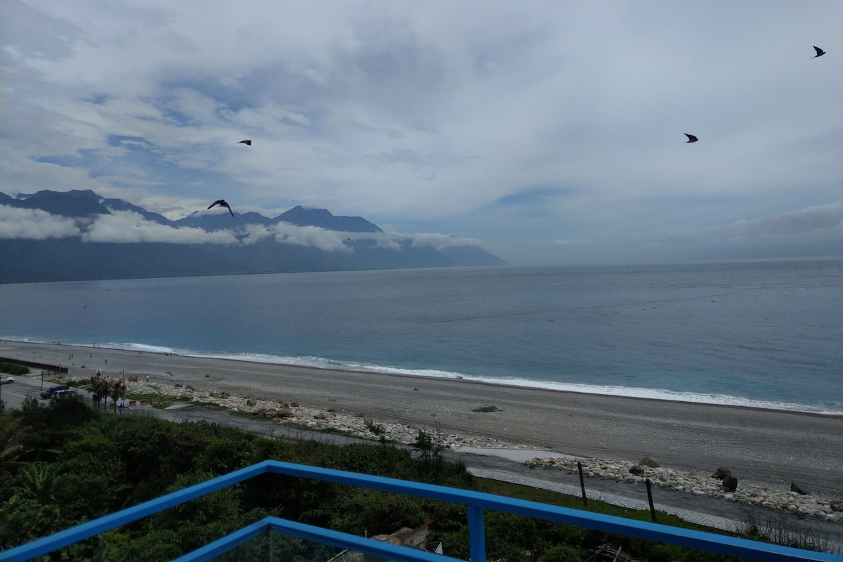 A coastal view with a beach, ocean, and mountains in the background.