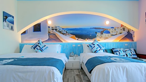 A hotel room with two beds, a view of a coastal town, and a mural of the sea and sky. - White Mediterranean (Hualien City)