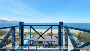 A balcony with two white chairs and a table, overlooking a beach with a clear sky and mountains in the distance. - White Mediterranean (Hualien City)