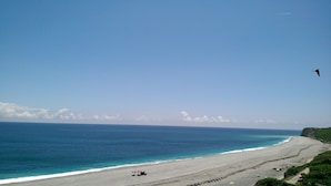 A beach with a clear sky, a sandy shore, and a bird flying. - White Mediterranean (Hualien City)