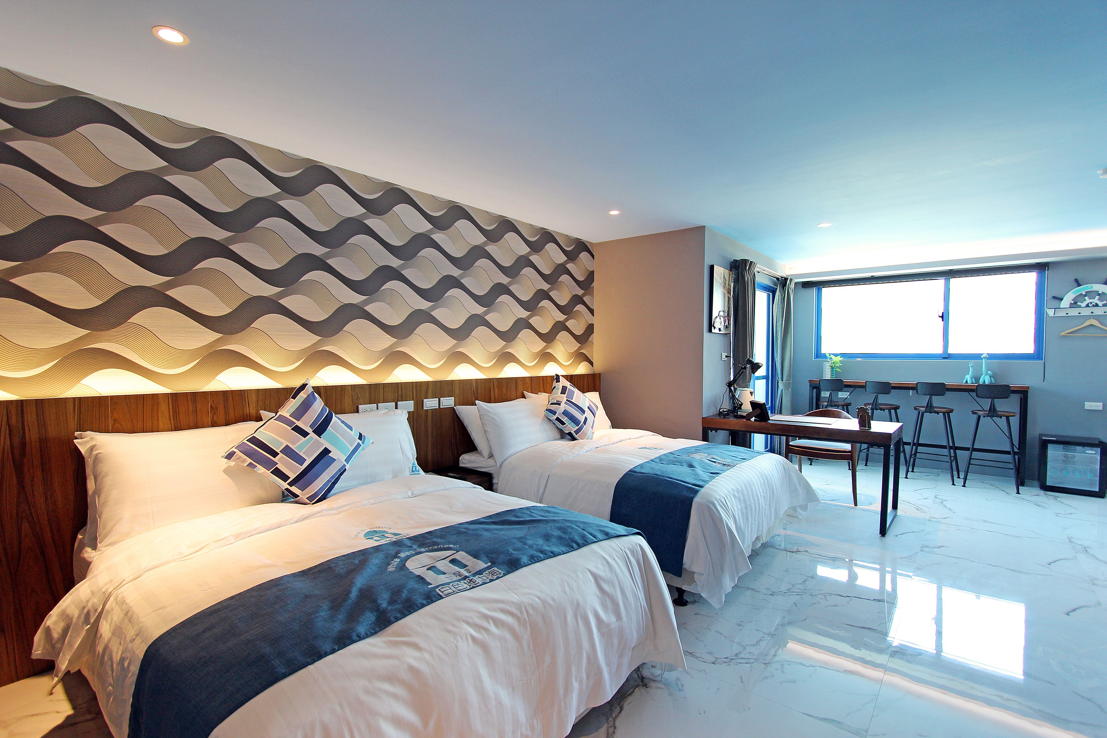 A hotel room with two beds, a desk, and a chair.