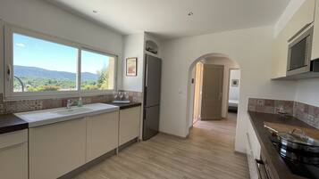 A modern kitchen with a large window, wooden flooring, and a view of the outdoors.