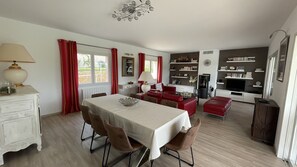 Un comedor con una mesa lista para cuatro personas, un sofá y un televisor al fondo.