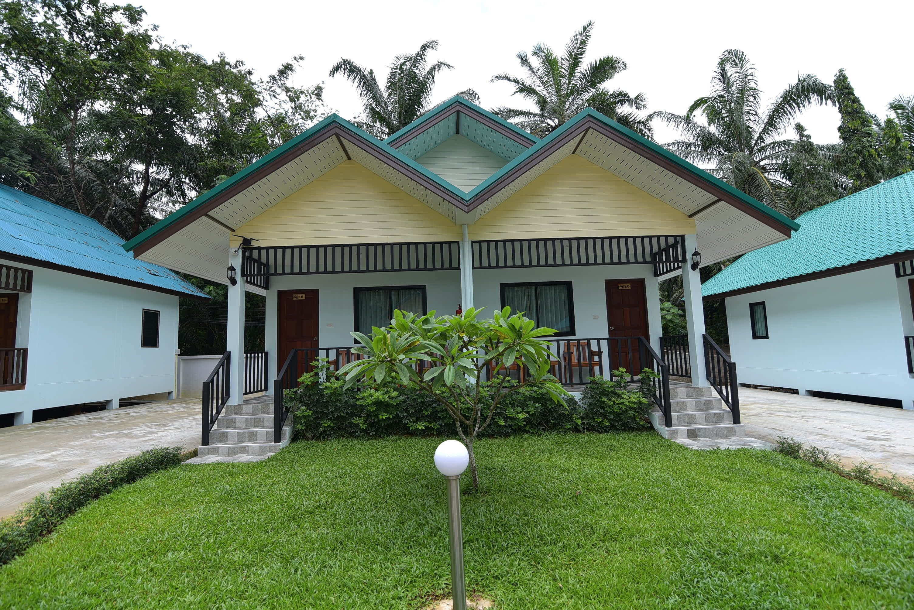 A two-story building with a central porch, surrounded by a well-maintained lawn and palm trees.
