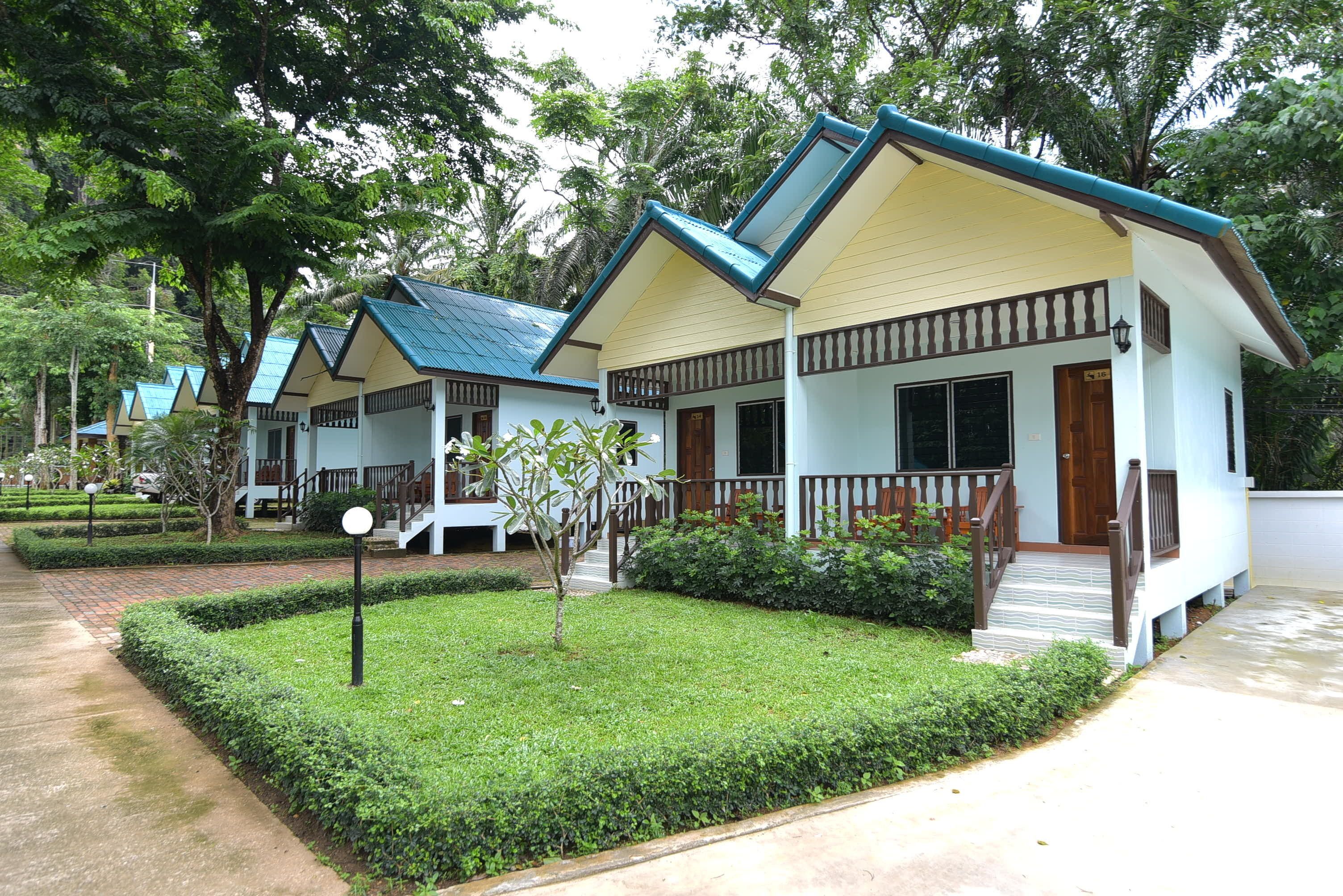 A row of bungalow-style buildings with a uniform architectural design, featuring a flat roof, a balcony, and a front porch.