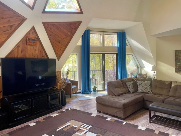 A living room with a large flat-screen TV, a sectional sofa, and a patterned rug.