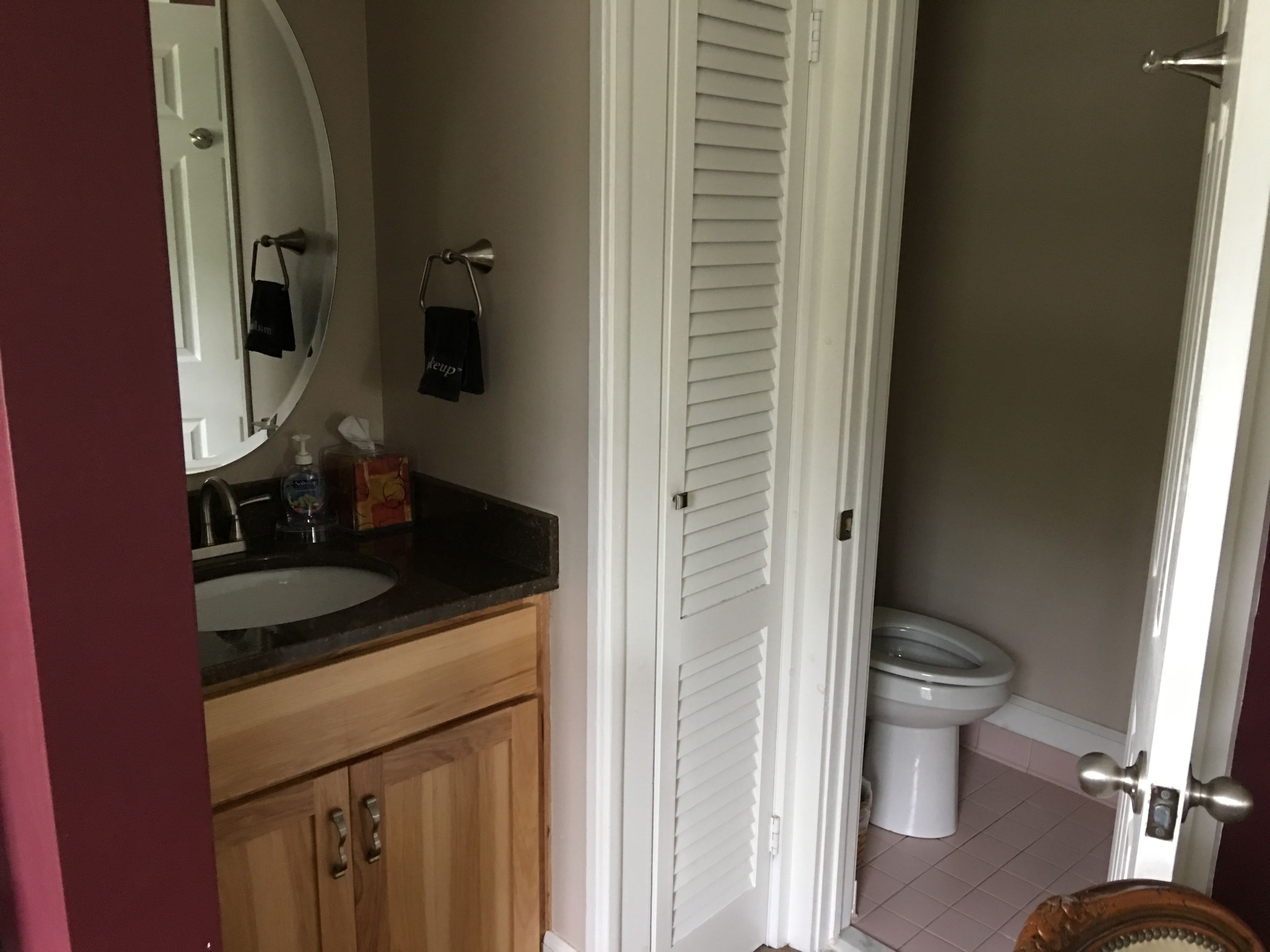 A bathroom with a wooden vanity, a white toilet, and a mirror.