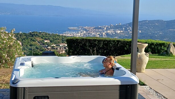 A hot tub with a view of a coastal city and mountains. - Gîte-Sassone, gîte with swimming pool, jacuzzi and panoramic sea view. (Ajaccio)