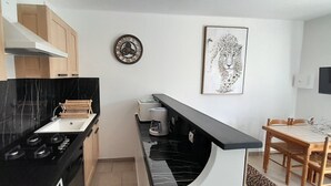 A modern kitchen with black marble countertops, wooden cabinets, a built-in stove, and a coffee machine. - Gîte-Sassone, gîte with swimming pool, jacuzzi and panoramic sea view. (Ajaccio)