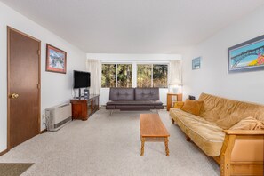 Relax in this inviting living room with a large window, comfortable sofa, and cozy coffee table.