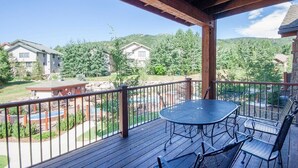 A wooden deck with a table and chairs, overlooking a residential area with houses and greenery.