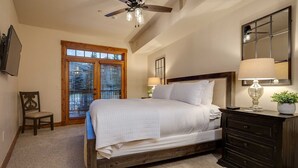 A bedroom with a wooden bed, a nightstand with a lamp, a dresser, and a ceiling fan.