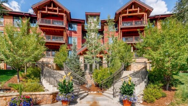 A multi-story building with balconies, a central staircase, and surrounding greenery.