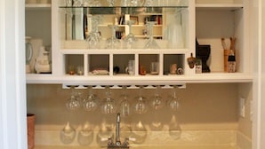 A kitchen with a glass-fronted wine rack, a dishwasher, and white cabinetry.
