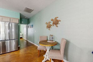 A kitchen with a stainless steel refrigerator, a round wooden table with two chairs, and two wall-mounted turtle decorations. - Welcoming condo with W/D & pool - near the beach (Corpus Christi)