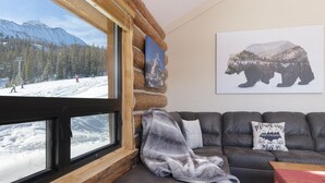 A cozy cabin interior with a large window overlooking a snowy mountain landscape.