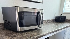 Un microondas de acero inoxidable sobre una encimera de granito, sobre un refrigerador empotrado con un cajón congelador.