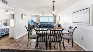 A dining area with a glass table, black chairs, a ceiling fan, and a view of the ocean. - Beachfront Condo, AshWorth, Free Wifi, Pools, Hot Tub | AshWorth - 1806 (North Myrtle Beach)