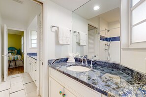Bathroom features a large mirror, sink, and shower area, with a door leading to a separate room.