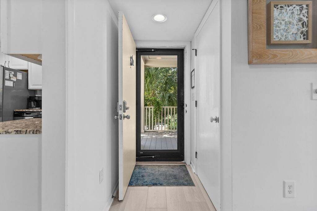A narrow hallway leading to a door with a view of a balcony.