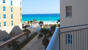 A view of a beach from a balcony with a clear blue ocean and a sandy walkway lined with palm trees. - BEACH FRONT! Waterscape A411 SLEEPS 8 OCEAN FRONT! LAZY RIVER! (Fort Walton Beach)