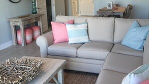 A living room with a sectional sofa, a wooden coffee table, and a rug. - BEACH FRONT! Waterscape A411 SLEEPS 8 OCEAN FRONT! LAZY RIVER! (Fort Walton Beach)