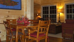 A wooden interior with a dining table, chairs, and a fireplace.