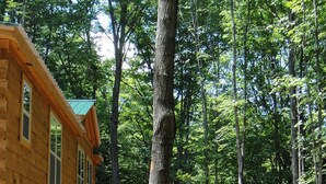 A wooden cabin with a balcony and a staircase leading to a deck.
