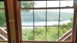 Un bagno con una vasca, una finestra che si affaccia su un lago e una foresta, e un appendi asciugamani.