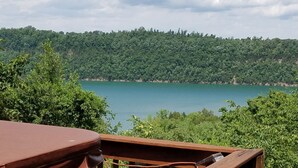 Vista di un lago circondato da una fitta foresta, con un pontile di legno in primo piano.
