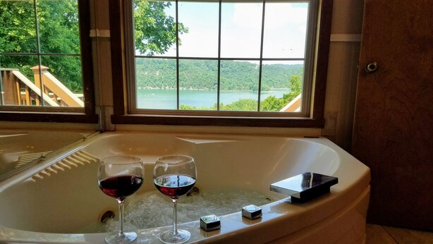 Una vasca da bagno con due bicchieri di vino rosso e un telecomando.