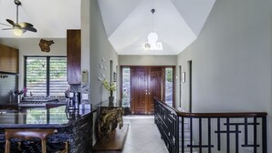 Una cocina moderna con una isla central, taburetes de bar y un ventilador de techo.