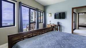 Un dormitorio con una cama grande, un escritorio, una silla y una televisión en la pared.