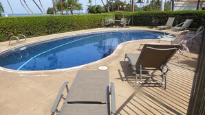 A swimming pool with lounge chairs and a view of the ocean. - FULL OCEAN VIEW, 2nd Floor 2 BR/1 BA,  BEST STAND-UP PADDLEBOARDING ON MAUI! (Kihei)