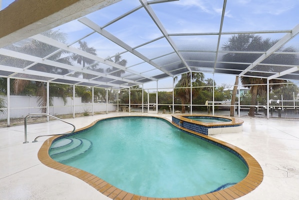 Relax by the oval-shaped pool, surrounded by a transparent roof and a white fence.
