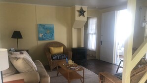 A living room with a sofa, a wicker chair, a coffee table, a lamp, a television, and a star decoration on the wall.