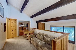Relax in this inviting room with a high ceiling, sofa, dining table, and window offering a view of the outdoors.